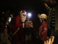 A Lebanese caver from the(ALES) disguised as Santa Claus, distributes gifts to children of the Association members and their comrades as the cavers celebrate with them Christmas inside a cave in the village of Rweiss nearly at 2000 meters above sea level in the Lebanese mountains north of Beirut.
