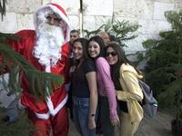 Israeli women pose for a picture with a Palestinian man dressed as Santa Claus standing between Christmas trees at a municipality distribution point at Jaffa Gate in Jerusalem&#039;s old city, ahead of Christmas celebrations.