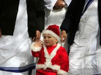 A Palestinian Christian boy wearing a Santa Claus costume waves during a ceremony ahead of Christmas attended by the head of the Roman Catholic Church in the Holy Land, the Latin Patriarch of Jerusalem Fuad Twal, outside the Latin Catholic Church in Gaza City.