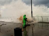 A municipality worker clears the mud as high waves rip off paving stones on Beirut's Mediterranean promenade.