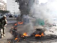 A Lebanese soldier disperses burning tires set alight by supporters of the Future Movement.