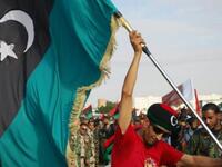 A Libyan man waves his new national flag during a ceremony announcing the liberation for the country in the eastern city of 
Benghazi. The new flag chimes in with the new chapter of hope for Libya. It also promises a return to Islamic values, 
with the reinstatement of rights to marry more than one wife, as well as exclusively Islamic banking.