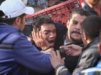 Anti-government protestors surround a supporter of President Mubarak after he was beaten in Tahrir Square.