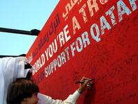 A Qatari man carrying his daughter writes a message on a board at Doha's traditional souk in support of his country's bid to host the 2022 World Cup before the tiny Gulf state was chosen by FIFA as a host.