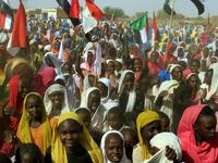 Sudanese women wave their national flag as they wait for the arrival of special envoys in the Shangil Tobaya area for displaced people in North Darfur state (AFP)