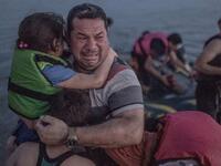 لاجئ يحتضن أولاده خلال بكائه بفرحة وصول قاربهم إلى إحدى الجزر اليونانية.