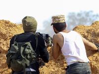 Libyan fighters loyal to the Government of National Accord (GNA) take cover behind a dirt barrier during clashes with forces loyal to strongman Khalifa Haftar south of the capital Tripoli's suburb of Ain Zara, on April 10, 2019. Mahmud TURKIA / AFP