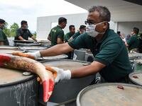 A member of a wildlife personnel team displays a seized ivory tusk before the confiscated ivory was destroyed at the Kualiti Alam Waste Management centre in Port Dickson on April 30, 2019.  Mohd RASFAN / AFP