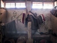 This picture shows blankets and clothes of South Sudanese refugees hanging in front of a wall filled with drawings and writings depicting scenes from home in a refugee transition camp for refugees who have just arrived in Aru. JOHN WESSELS / AFP