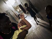 Willy, an inhabitant of the roca Agostinho Neto, an abandoned cocoa plantation of Sao Tome and Principe, plays with a child in a hall, of the hospital of the roca on May 29, 2019. Alexis HUGUET / AFP