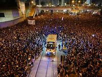 An ambulance is pictured surrounded by thousands of protesters dressed in black during a new rally against a controversial extradition law proposal in Hong Kong.  HECTOR RETAMAL / AFP