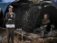 A mother and daughter pose in front of their makeshift shelter at the Samos refugee camp, just above the island's capital city of Vathy.  LOUISA GOULIAMAKI / AFP