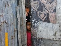 Palestinian children peep from behind a makeshift door at an empoverished neighbourhood in Gaza City on July 4, 2019.  MOHAMMED ABED / AFP