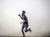 A Palestinian protester flees from tear gas fired by Israeli forces during protests along the border with Israel east of Khan Yunis in the southern Gaza strip on July 5, 2019.  SAID KHATIB / AFP