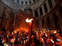 Christian Orthodox worshippers hold up candles lit from the ‘Holy Fire’ as they gather in the Church of the Holy Sepulchre in Jerusalem’s Old City on April 27, 2019. GALI TIBBON / AFP