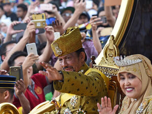 Brunei’s Sultan Hassanal Bolkiah and Queen Saleha ride in a royal chariot during a procession. (AFP/ File Photo)