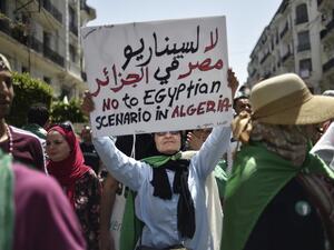 An Algerian woman raises a placard as she takes part in a weekly demonstration in the capital Algiers on June 14, 2019. (AFP/ File Photo)