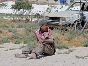 A young Syrian man sits on the ground after a bombing on an industrial area of Idlib, Northern Syria, on June 18, 2019. (AFP/ File Photo)