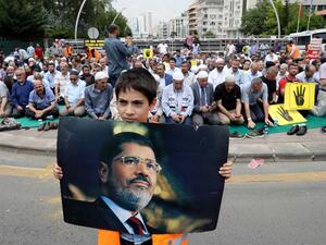 A boy holds a picture of the Egyptian President Mohamed Morsi during a symbolic funeral prayer on June 18,2019 in front of the embassy in Ankara. (AFP/ File Photo)