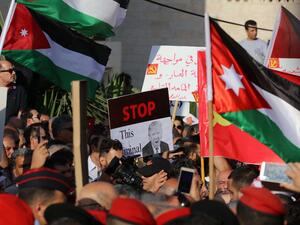 Protesters hold an anti-Donald Trump signs and Jordanian flags during the "March of Anger" demonstration leading to the US embassy headquarters in the Jordanian capital Amman on June 21, 2019, against the US President's "Deal of the Century" and the US-led Middle East economic conference in Bahrain. (Khalil MAZRAAWI / AFP)