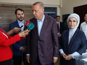 Turkish President Recep Tayyip Erdogan (C), flanked by his wife Emine (R), speaks to journalists after casting his ballot at a polling station, in Istanbul, on June 23, 2019, during local elections. (AFP/ File Photo)