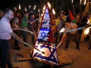 Palestinians burn a structure displaying the Israeli flag and a portrait of King Hamad al-Khalifa of Bahrain during protests against a US-led meeting this week in the Gulf kingdom on the Palestinian-Israeli conflict, in the West Bank city of Hebron on June 24, 2019. (AFP/ File Photo)