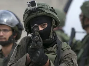 Israeli soldier aims his weapon at Palestinians. [Jaafar Ashtiyeh/AFP/Getty Images]