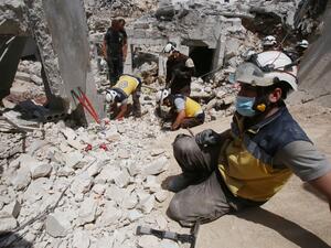 Members of the Syrian Civil Defence (White Helmets) clear debris as they search for bodies or survivors in a collapsed building following a reported regime air strike on the town of Ariha, in the south of Syria's Idlib province, on July 12, 2019. (AFP)