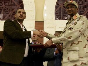 Sudanese deputy chief of the ruling miliary council Mohamed Hamdan Dagalo (R) and protest movement Alliance for Freedom and Changes leader Ahmad al-Rabiah shake hands after inking an agreement before African Union and Ethiopian mediators in Khartoum early on July 17, 2019. (AFP)