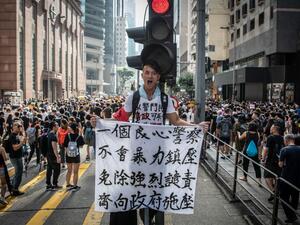 A protester in Wan Chai holds a sign denouncing police violence during a march against a controversial extradition bill in Hong Kong on July 21, 2019. Another huge anti-government march kicked off in Hong Kong on July 21 afternoon with seemingly no end in sight to the turmoil engulfing the finance hub, sparked by years of rising anger over Beijing's rule.  Laurel CHOR / AFP
