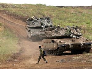 An Israeli soldier next to Merkava Mark IV tanks in the Golan Heights during a military drill on May 7, 2018. (AFP Photo/Jalaa Marey)