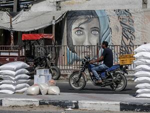 A Palestinian man rides his motorcycle outside an aid distribution centre run by the United Nations Relief and Works Agency (UNRWA) in the central Gaza Strip refugee camp of Bureij (AFP)