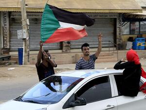 Sudanese demonstraters wave their national flag (AFP)