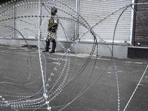 A security personnel stands guard behind a barbed fence wire during a lockdown in Srinagar (AFP)