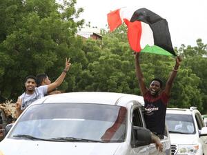 A Sudanese man waves a national flag as people celebrate outside the Friendship Hall in the capital Khartoum where generals and protest leaders signed a historic transitional constitution meant to pave the way for civilian rule in Sudan, on August 17, 2019. (AFP/ File Photo)