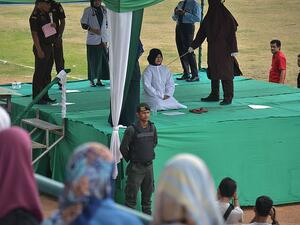 One woman pleading for the masked sharia officer to stop because she could not bear the pain. (AFP)
