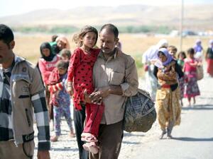 A displaced Iraqi man from the Ezidi community carries his daughter as they cross the Iraqi-Syrian border. (AFP /AHMAD AL-RUBAYE)