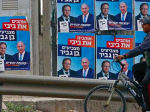 A Palestinian rides his bicycle past electoral campaign posters depicting Israeli Prime Minister Benjamin Netanyahu (right) and far-right politician Itamar Ben Gvir in the West Bank. HAZEM BADER/AFP