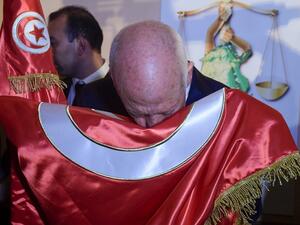 Conservative academic Kais Saied kisses the Tunisian flag as he celebrates his victory in the Tunisian presidential election in the capital Tunis  (AFP)