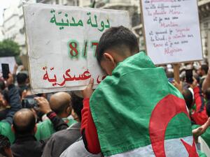 An Algerian boy rests his head on a placard that reads in Arabic "(we want) a civil state", during the 36th consecutive Friday anti-government demonstrations in the capital Algiers, on October 25, 2019. AFP