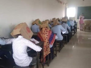 Students wearing cardboard boxes on their heads during an exam to discourage cheating (Twitter)