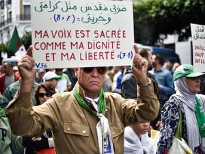 Protester in Algiers holds up sign that reads: 'My voice is sacred just like my dignity and my freedom' (AFP)