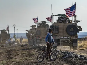 A Syrian boy on his bicycle looks at a convoy of US armoured vehicles patrolling fields near the northeastern town of Qahtaniyah at the border with Turkey, on October 31, 2019. US forces accompanied by Kurdish fighters of the Syrian Democratic Forces (SDF) patrolled part of Syria's border with Turkey, in the first such move since Washington withdrew troops from the area earlier this month, an AFP correspondent reported. Delil SOULEIMAN / AFP