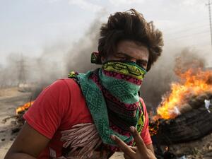 An Iraqi protester walks past burning tires as others block the road to Umm Qasr port during ongoing anti-government demonstrations in southern Iraq on November 7, 2019. A sit-in had cut the road to the Umm Qasr port, which brings in most food and medical imports through Basra, but it reopened later during the day. Hussein FALEH / AFP
