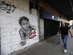 A man walks past a graffiti drawn on the wall of a building at the al-Nour Square in the northern port city of Tripoli  (AFP)