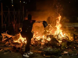 A protester pours petrol onto a burning barricade at the Chinese University of Hong Kong (CUHK), in Hong Kong early on November 13, 2019. Hong Kong pro-democracy protesters fought intense battles with riot police on a university campus and paralysed the city's upmarket business district Tuesday. ( Anthony WALLACE / AFP)