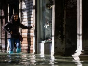 A woman carefully walks across a flooded arcade on November 14, 2019 in Venice. Much of Venice was left under water after the highest tide in 50 years ripped through the historic Italian city, beaching gondolas, trashing hotels and sending tourists fleeing through rapidly rising waters. Filippo MONTEFORTE / AFP