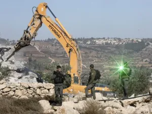 An Israeli border guard points a laser light at the camera as others keep watch while a bulldozer demolishes Palestinian houses near al-Arub camp, on the outskirts of the West Bank town of Hebron (AFP)