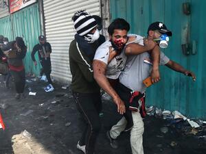 In this file photo taken on November 15, 2019, Iraqis carry a protester wounded after being struck by a tear gas canister amidst clashes with security forces at the capital Baghdad's Khallani square during ongoing anti-government demonstrations. At least 3,000 people who have been maimed in Baghdad and southern Iraq since anti-government protests erupted on October 1, according to the NGO Iraqi Alliance for Disabilities Organisation (IADO). After decades of back-to-back conflicts, Iraq is in the thick of it
