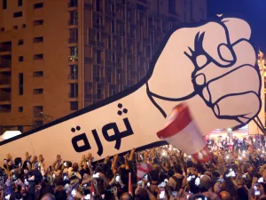 Lebanese demonstrators raise a new giant sign of a fist that bears the Arabic word "revolution" on it, in the Lebanese capital Beirut's Martyr's Square on November 22, 2019, after the sign was burnt overnight by unknown perpetrators. (AFP/ File )